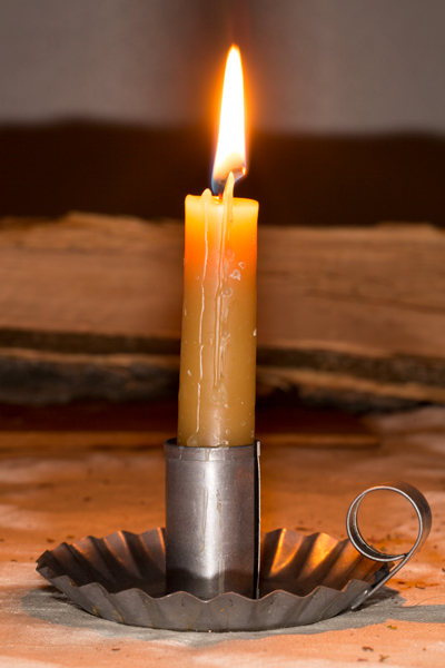 A solitary beeswax candle burns in reflective meditation