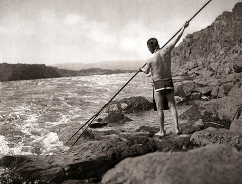 Historic photo of an Indian spearing salmon in the wild flowing Columbia River