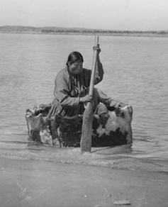 An Indian woman paddles a small, round boat