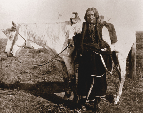Southwest Indian standing in front of a white horse