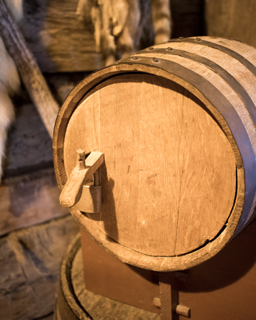 Tankard of foamy drink behind earthern jugs