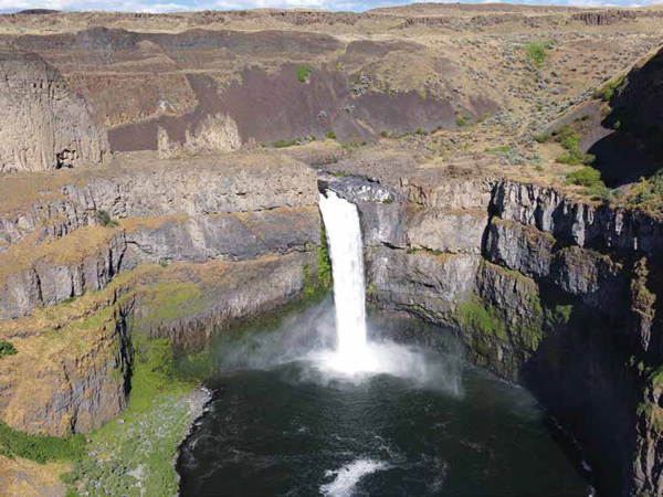 Tiny waterfall surrounded by tall layers of basalt rock shows evidence of colossal Lake Missoula Floods