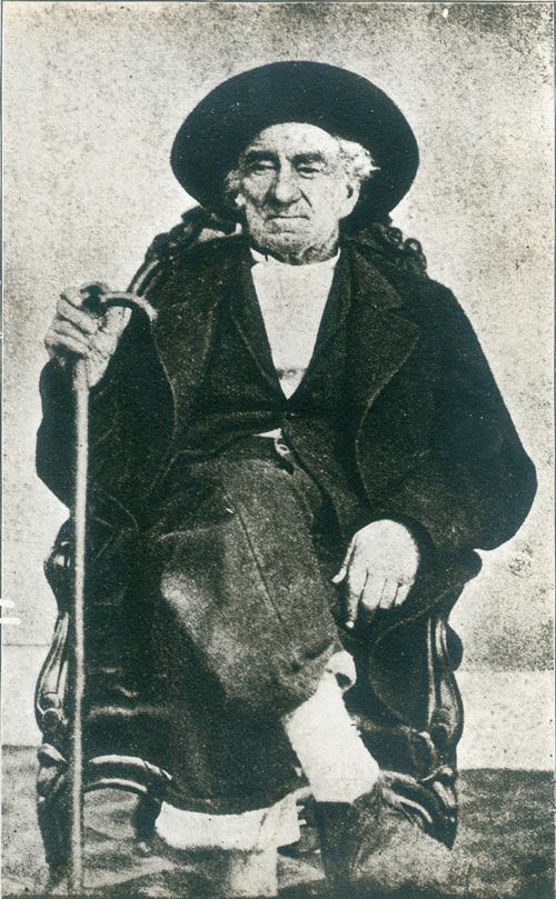 Joseph Robidoux IV as an old man with a cane sitting on a chair