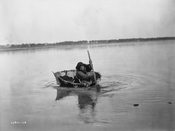 Historic photo of an Indian women paddling a small round boat