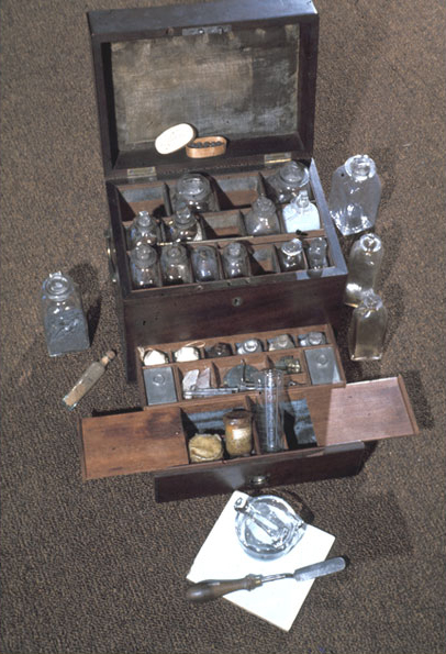 interactive photo of a wood box with small bottles of labeled medicines