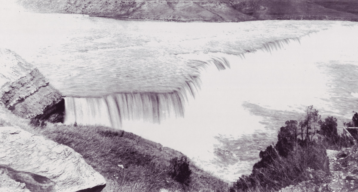 A wide river falls over a steep ledge at Rainbow Falls