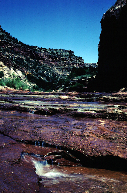 shallow creek flowing over large slabs of rock