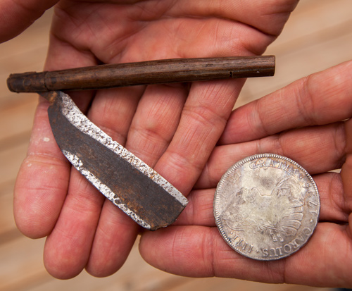 Two hands holding a straight razor and old silver coin