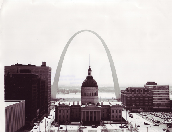 A large arch behind a dome and in front of the Mississippi River