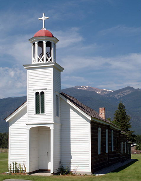 A plain, white church with two additions in the back