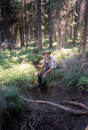 Steve Russell wearing overalls sitting on a forest trail