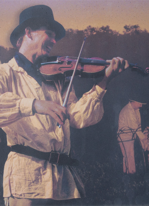A fiddler in a white linen shirt and round top hat