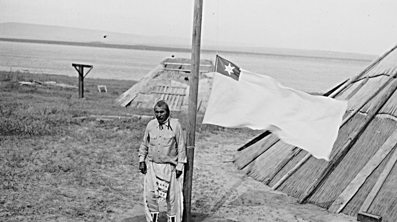 Twentieth-century Indian next to a tule reed mat lodge by the Columbia River