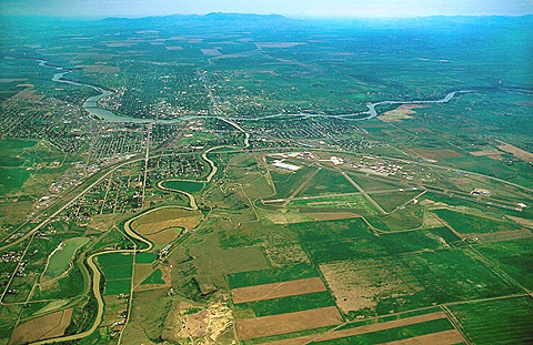 River winding through flat farm land to a much a larger river