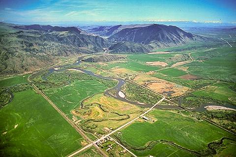 Rivers winding through flat farmlands just before entering mountains