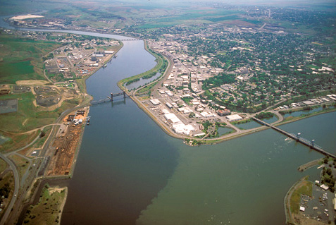 Two wide rivers, slowed by a dam, come together in a dity