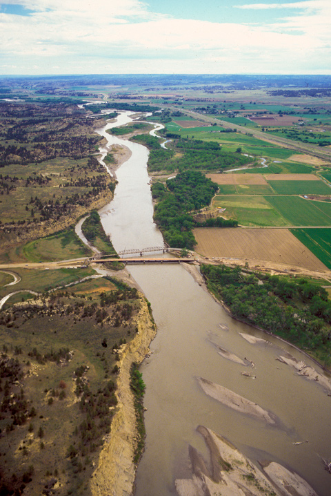 Aerial photo of Bundy Bridge crossing the Yellowstone River as it flows through a wide, flat valley