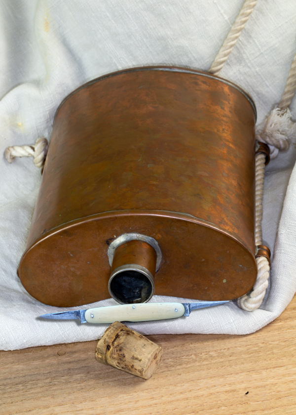 A small knife rests on an empty copper canteen