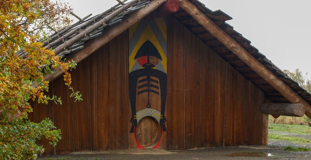Large cedar lodge with a painted figure of a Chinookan man