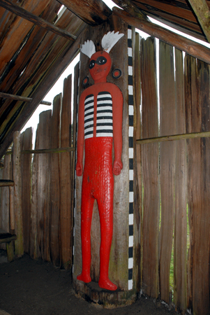 Wood sculpture of a red man holding up the roof