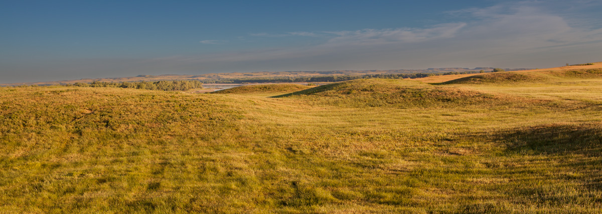 Field with large mounds looking over the river