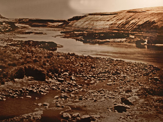Historic photo of a small rocky creek entering a river